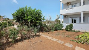 Un bâtiment moderne à deux étages, doté d’un jardin agrémenté de diverses plantes et d’un sentier en pierre.