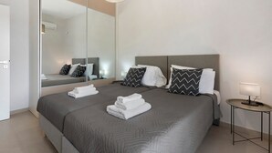 Une chambre d’hôtel moderne avec un grand lit, une table de chevet, un miroir et une lampe.