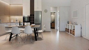 Une cuisine moderne avec coin repas, dotée d’appareils électroménagers en acier inoxydable, de meubles blancs et d’un design minimaliste.