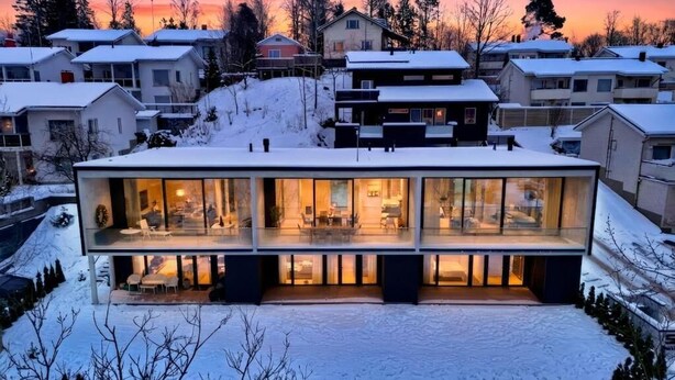 A modern house with large glass windows, a flat roof, and a snow-covered landscape. - Smart Home. Cinema. Sauna. Sonos Audio (Espoo)