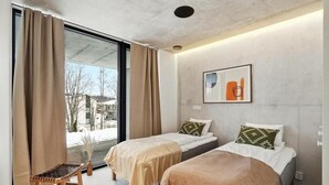 A modern hotel room with two beds, a large window, a chair, and a framed picture on the wall. - Smart Home. Cinema. Sauna. Sonos Audio (Espoo)