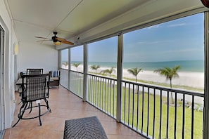 Ein Balkon mit Blick auf den Strand, Deckenventilator und Gartenmöbel.