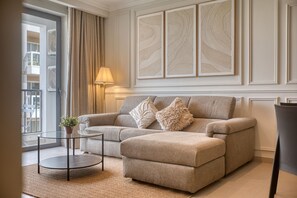 Ein Wohnzimmer mit einer Couch, Hocker und einem kleinen Tisch mit Lampe.