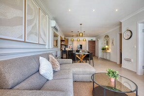 Ein modernes Wohnzimmer mit Ecksofa, Glastisch und Essbereich mit Tisch und Stühlen.