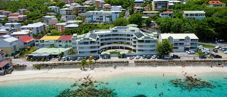Un hotel frente al mar con varios pisos, estacionamiento y vista a la playa.