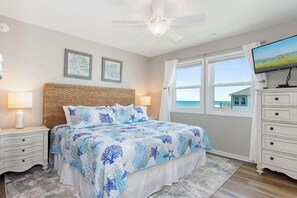 A bedroom with a bed, nightstands, a dresser, a ceiling fan, and a TV. - Oceanfront Condo w/ Panoramic Views, Whirlpool Tub & Beach Access (Emerald Isle)