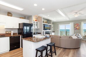 A modern kitchen with a central island, a built-in refrigerator, and white cabinetry. - Oceanfront Condo w/ Panoramic Views, Whirlpool Tub & Beach Access (Emerald Isle)