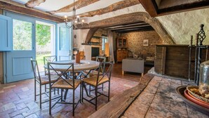 A rustic interior with exposed wooden beams, a stone wall, a round table with chairs, and a fireplace. - Casa Biloslavi with pool (Groznjan)