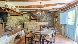 A rustic stone interior with a round table and chairs, a stone fireplace, and a wooden ceiling. - Casa Biloslavi with pool (Groznjan)