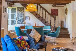 Een gezellige woonkamer met een bank, stoelen, een salontafel en een trap.