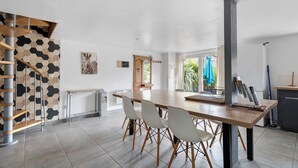 Eine moderne Küche mit einem Holztisch, weißen Stühlen, einer Treppe und Blick ins Freie.
