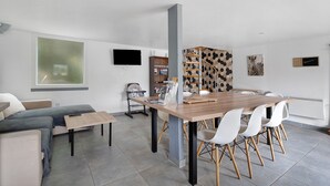 Ein moderner Wohnraum mit Essbereich, einer Couch, einem Fernseher und einer Treppe.