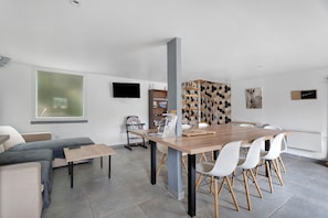 Ein moderner Wohnraum mit Essbereich, einer Couch, einem Fernseher und einer Treppe.