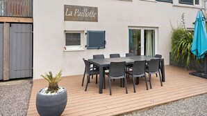 Eine Terrasse mit Tisch und Stühlen, einem Blumentopf und einem Schild mit der Aufschrift 'La Paillotte'.