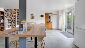 Ein moderner Essbereich mit einem Holztisch, Stühlen, einem Bücherregal und einem Schrank.