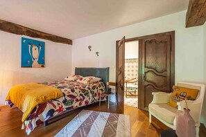 A bedroom with a bed, a sofa, a wooden door, and a painting on the wall. - Suite La Denise in the Heart of the Vineyards (Curtil-Vergy)
