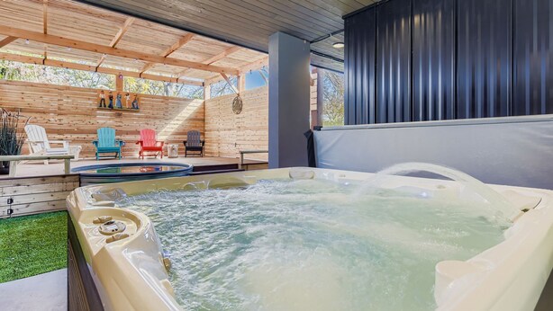 A hot tub with a wooden deck, outdoor seating, and a covered area with a view of trees. - 4 BR Home, Hot Tub, Cowboy CHILL Pool, Private Deck/Pergola, 3-minutes to Downtown Austin! (Austin)