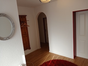 Ein Flur mit einem hölzernen Kleiderschrank, einem Spiegel und einem roten Teppich.