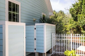 Une maison bleu clair avec une clôture blanche en bois, un porche abrité et un petit jardin.