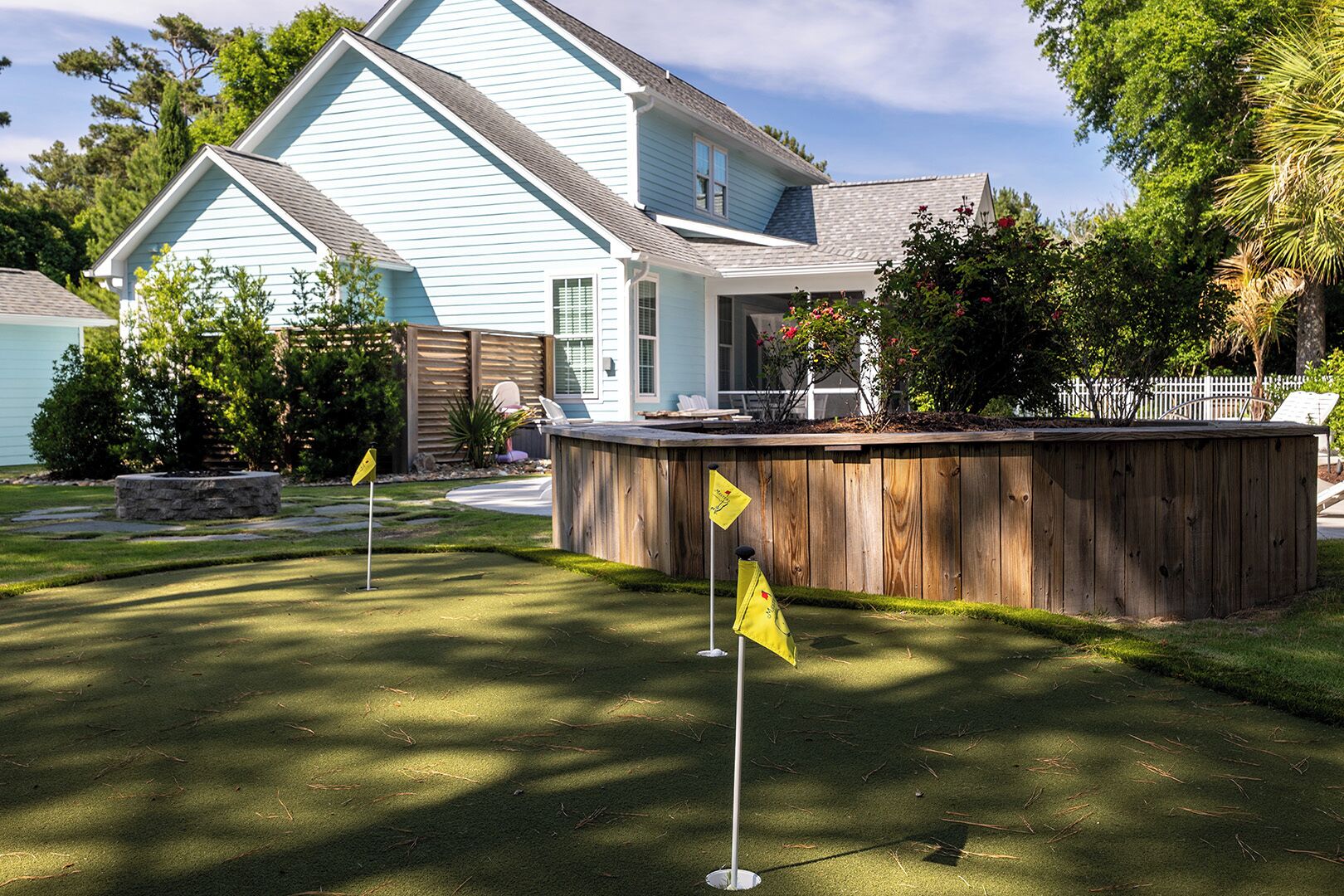 Il s’agit d’une propriété résidentielle comprenant une maison bleu clair, une terrasse en bois et une pelouse bien entretenue.