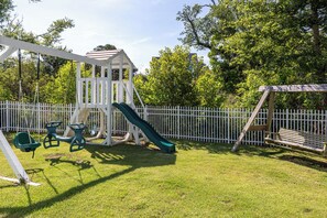 Ein Spielplatz mit Schaukeln, einer Rutsche und einer Holzbank.
