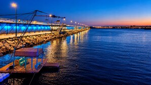 A waterfront promenade with a wooden dock, stone steps, and a bridge in the background. - Your Charming Home in La Siesta (Torrevieja)
