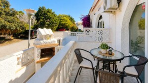 A balcony with a table and chairs, a grill, and a decorative fountain. - Your Charming Home in La Siesta (Torrevieja)