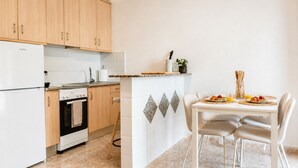 A kitchen with wooden cabinets, a stove, and a dining area with a table and chairs. - Your Charming Home in La Siesta (Torrevieja)
