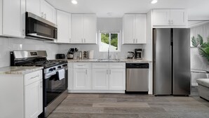 A modern kitchen with white cabinets, stainless steel appliances, and a window providing natural light. - Bright & Modern 2-Story Near Northwestern (Evanston)