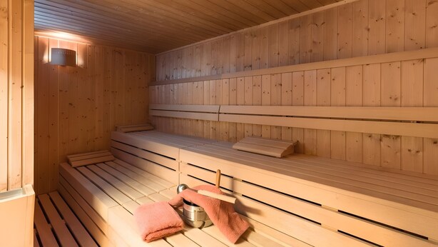 Eine Holzsauna mit Bänken und einem Handtuchhalter.