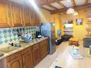 Una cocina con armarios de madera, un refrigerador, una cafetera y un televisor.