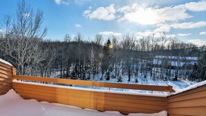 Un ponte di legno con vista su una foresta innevata e un cielo sereno.