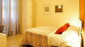A hotel room with a bed, a desk, a chair, curtains, and two framed pictures on the wall. - B&B La Rocca  (Spoleto)