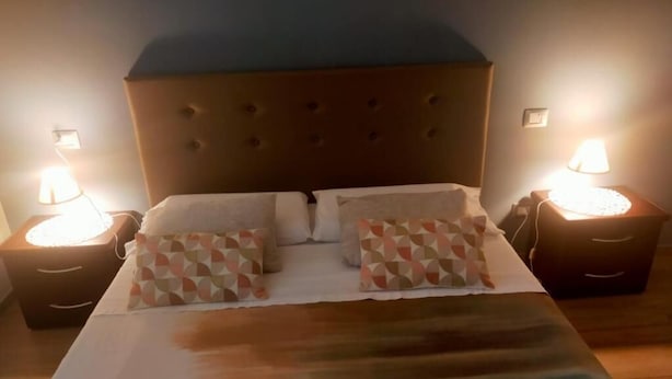 A bed with a tufted headboard, two bedside lamps, and patterned pillows. - B&B La Rocca  (Spoleto)