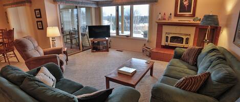 A living room with a fireplace, a television, and a ceiling fan.