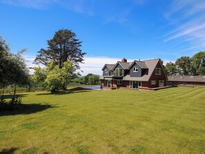 A two-story house with a large lawn, a tree, and a clear blue sky. - Westington Hall (Leominster)