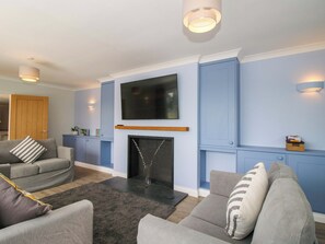 A living room with a fireplace, grey sofas, a flat-screen TV, and blue walls. - Westington Hall (Leominster)
