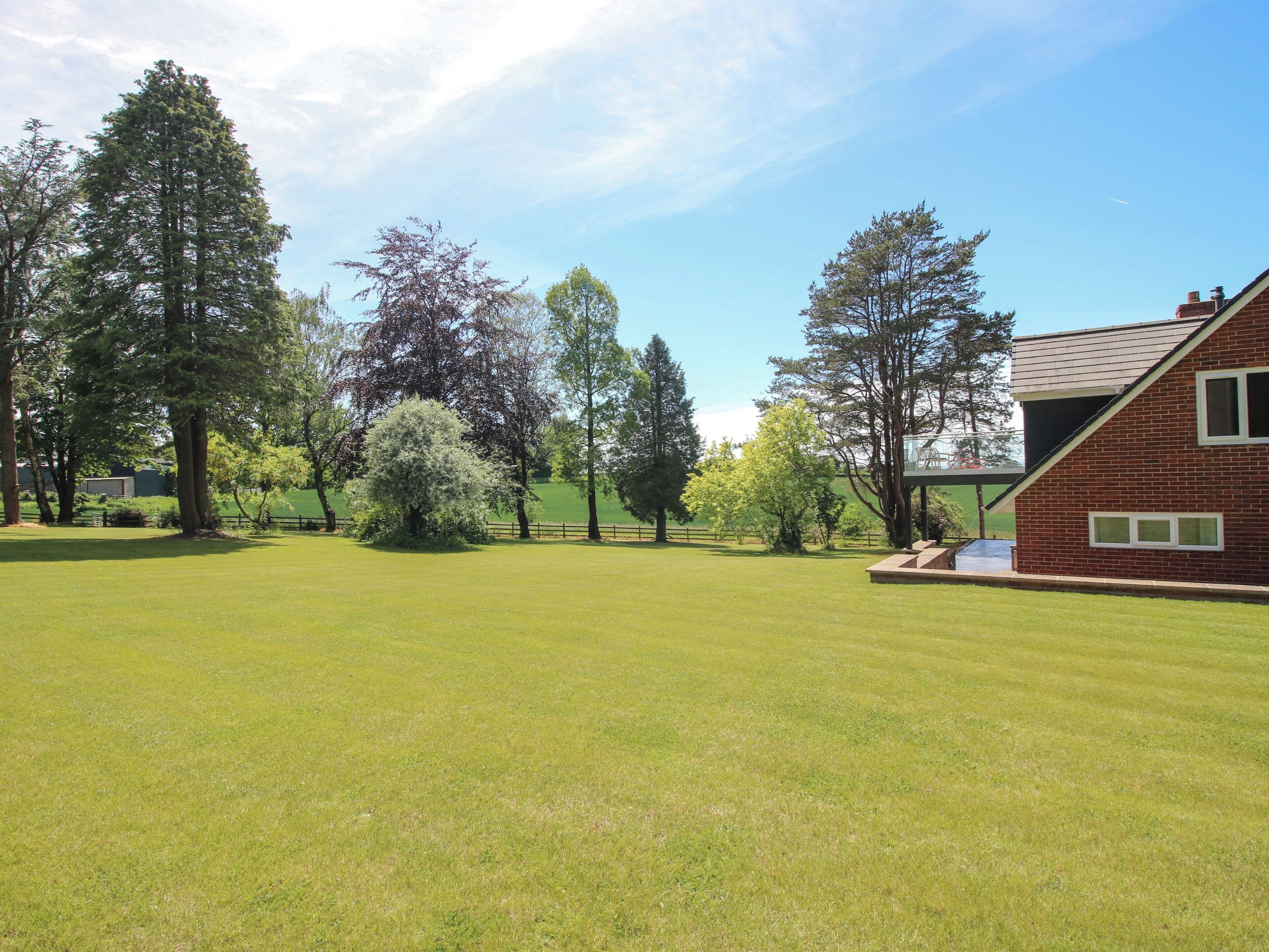 A grassy field with trees and a brick building.