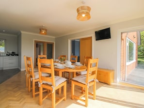 A dining area with a round table, wooden chairs, and a television mounted on the wall. - Westington Hall (Leominster)