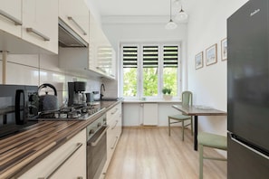 Eine moderne Küche mit einer Holzarbeitsplatte, eingebauten Geräten und einem Fenster mit Fensterläden.