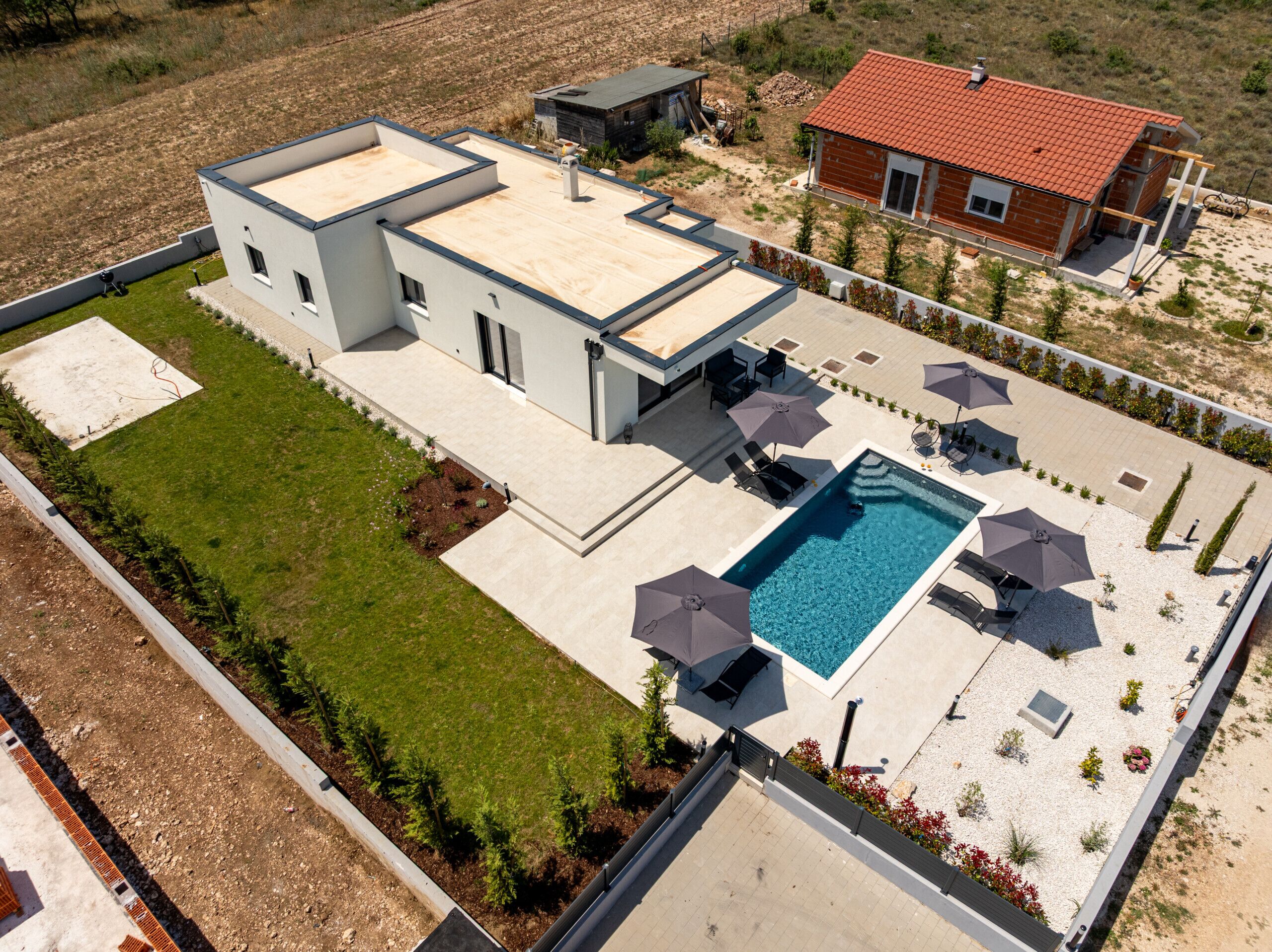 A modern house with a swimming pool, patio furniture, and a well-maintained lawn.