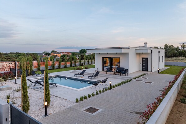 A modern house with a swimming pool, outdoor seating, and a view of the surrounding landscape. - Villa Enija Zadarvillas (Nin)