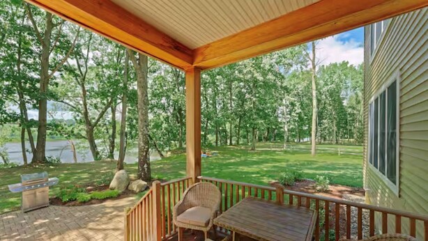 A covered deck with wicker furniture, a table, and a bench. - Riverfront on the Hudson with nature to explore (Mechanicville)