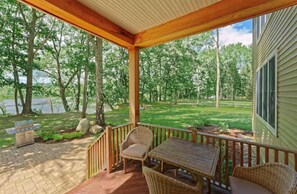 Une terrasse couverte, aménagée avec des meubles en osier, une table et un banc.
