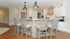 A kitchen with a central island, white cabinets, and a dining area with chairs. - Riverfront on the Hudson with nature to explore (Mechanicville)