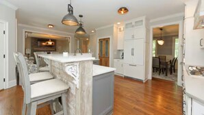 A kitchen with a central island, white cabinetry, and a dining area with chairs and a table. - Riverfront on the Hudson with nature to explore (Mechanicville)