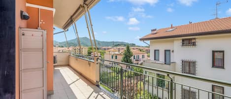 A balcony with a view of a town, a door, and a railing.
