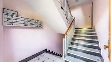 Una escalera con barandilla, piso de mármol y buzón empotrado en la pared.