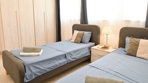 A hotel room with two beds, a nightstand with a lamp, and a wooden wall. - Exceptional Sea View Apart St Paul's Bay (St. Paul's Bay)
