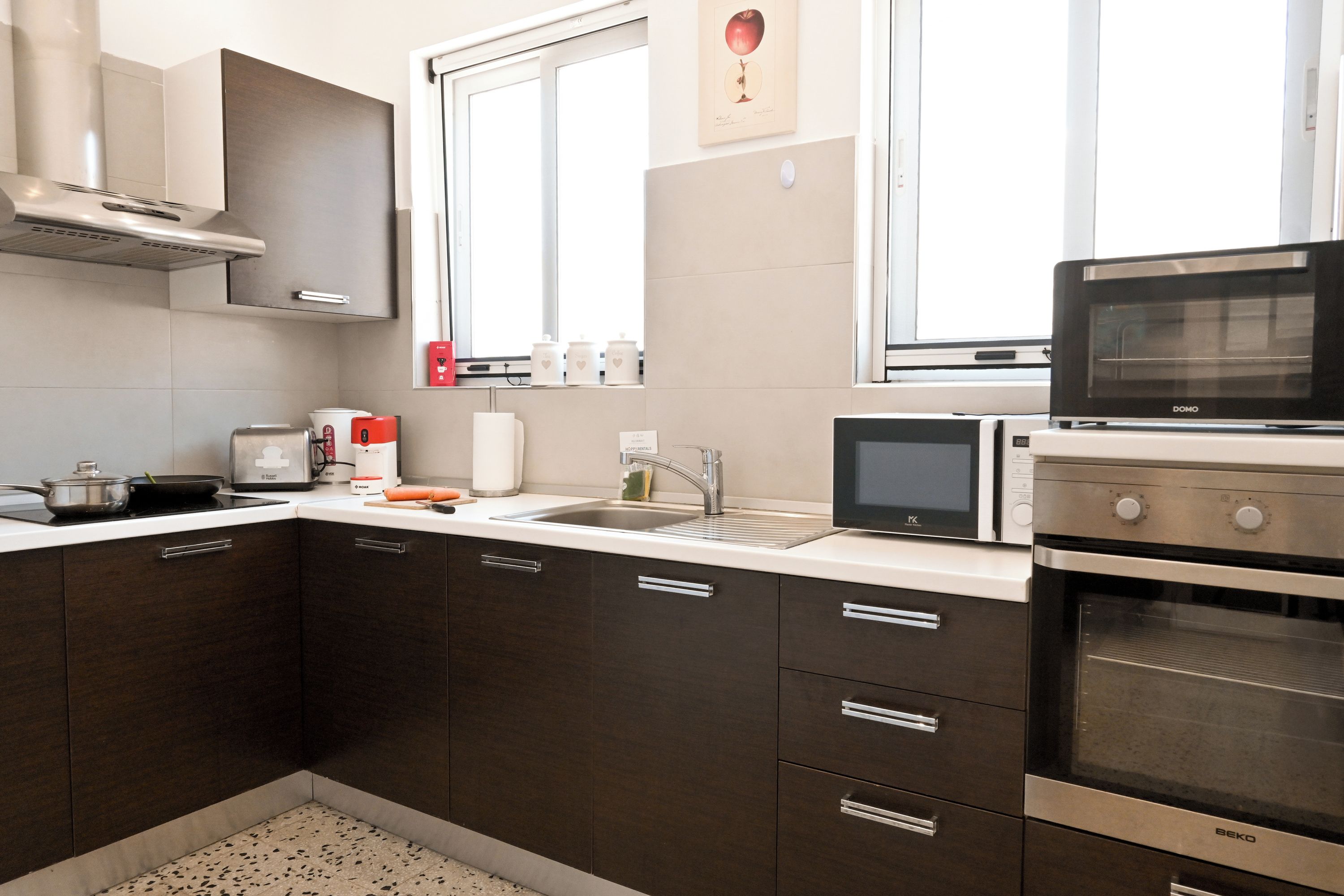 Una cocina moderna con armarios oscuros, una campana extractora de acero inoxidable, un microondas y un horno.